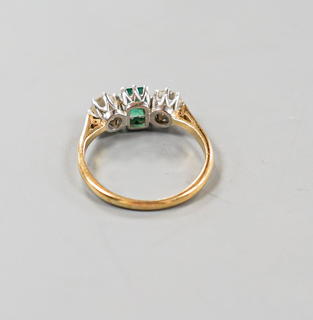 A modern 18ct gold, emerald and diamond set three stone ring, size O, gross weight 3.1 grams.